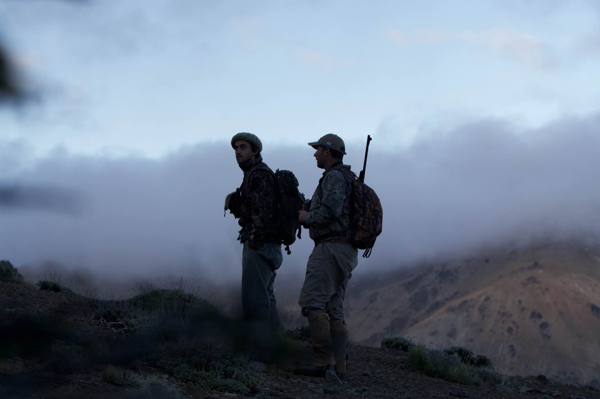 Two hunters on a ridge above the clouds